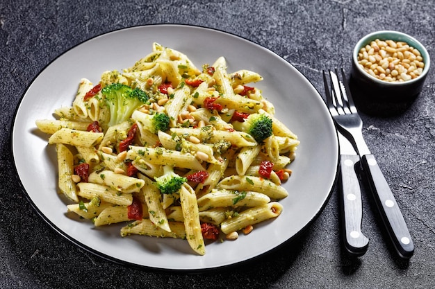 Pasta penne con pesto de brócoli con tomates secos y piñones en un plato