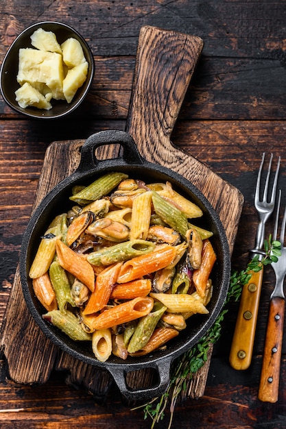 Pasta penne en salsa de crema con mariscos. Fondo de madera oscura. Vista superior.