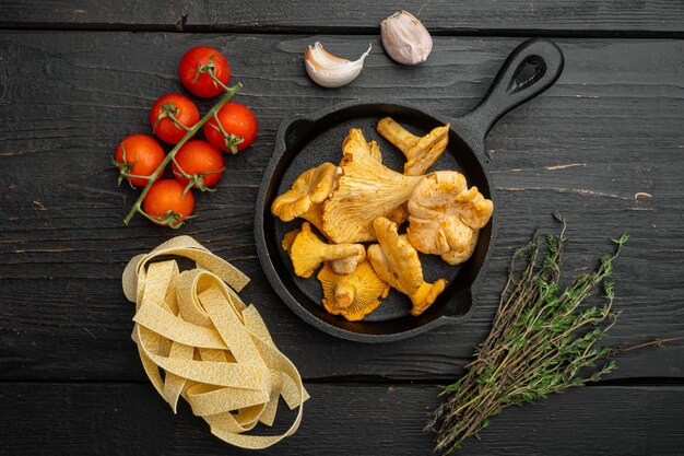 Pasta-Pfifferlinge-Zutaten-Set, auf schwarzem Holztischhintergrund, Draufsicht flach