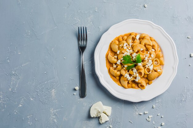 Pasta pipa o rigat com molho de grão de bico e tomate, polvilhado com queijo feta e coentro