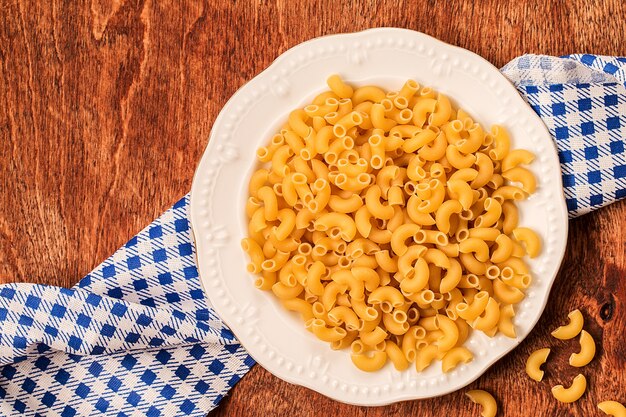 Pasta en plato blanco sobre mesa de madera. Vista superior