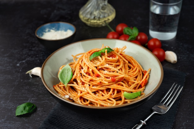 Pasta en un plato con salsa de tomate sobre fondo negro