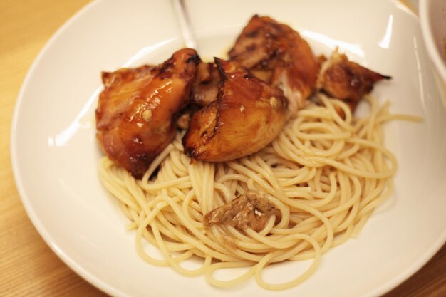 pasta con pollo teriyaki en un plato blanco