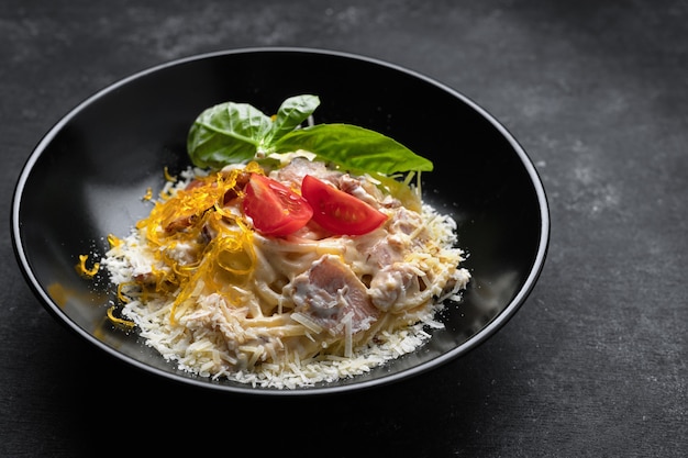 Pasta con queso de carne y albahaca sobre una placa negra