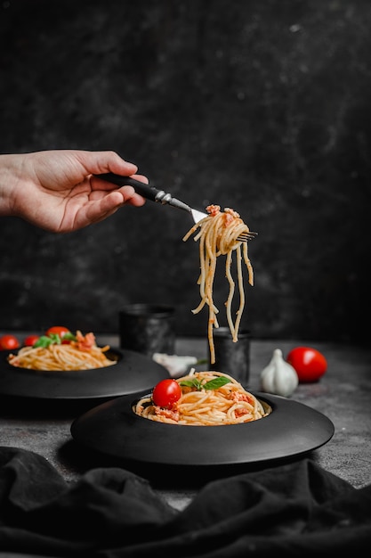 Pasta con queso feta y tomates al horno en una placa negra Espaguetis