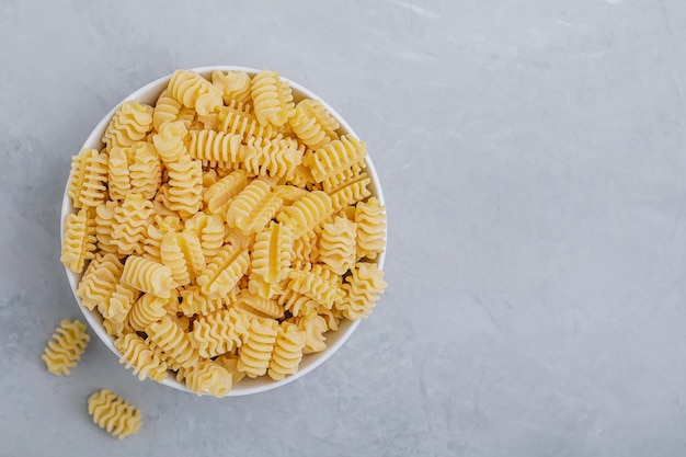 Pasta Radiatori sin cocer la pasta en un tazón blanco sobre fondo de piedra gris