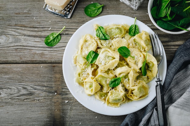 Pasta de ravioles italianos con espinacas y ricotta sobre fondo rústico de madera