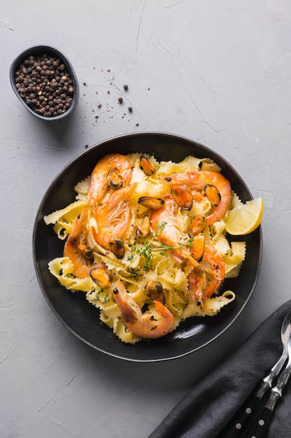 Pasta reginelle con mariscos, camarones, mejillones en mesa gris. Plato tradicional en restaurante italiano.