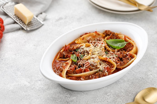 Pasta rellena con salsa de carne boloñesa, tomates, queso, albahaca en un plato para hornear Pasta boloñesa italiana