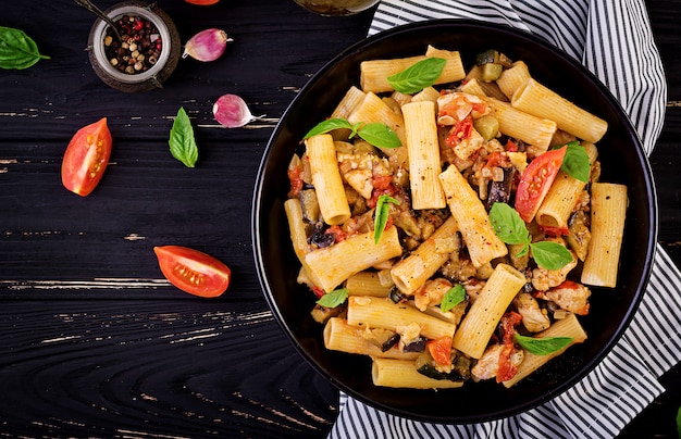 Pasta rigatoni con carne de pollo, berenjenas en salsa de tomate en un tazón. cocina italiana