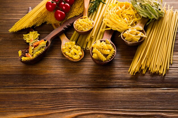 Pasta rizada en cucharas sobre una mesa oscura, diferentes variedades de pasta.
