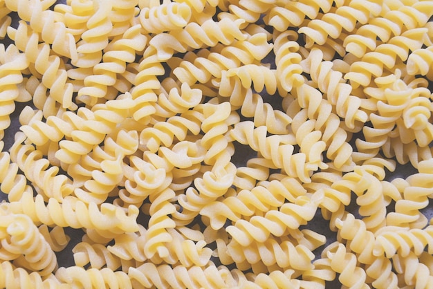 Pasta rohe Makkaroni auf Holzhintergrund Nahaufnahme rohe Makkaroni Spiralnudeln ungekochte köstliche Fusilli-Nudeln zum Kochen von Speisen