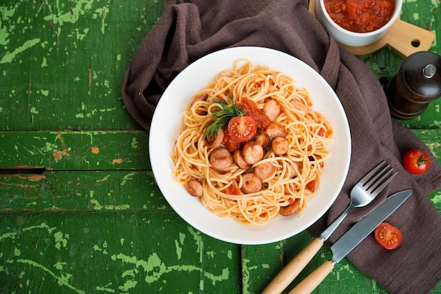 Pasta con salchichas y salsa de tomate sobre un fondo rústico, vista superior, espacio de copia