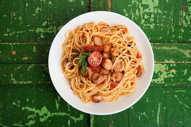 Pasta con salchichas y salsa de tomate sobre un fondo rústico, vista superior