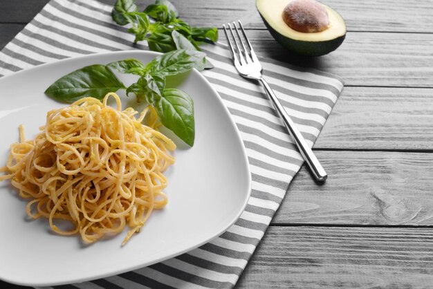 Pasta con salsa de aguacate y albahaca en primer plano de la mesa de madera