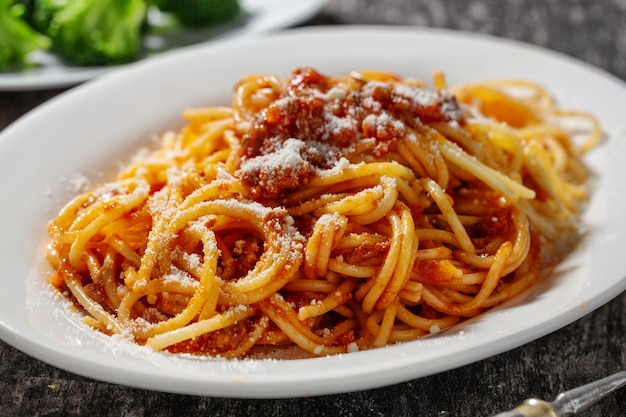 Pasta con salsa boloñesa en un plato sobre fondo de madera rústica. De cerca.