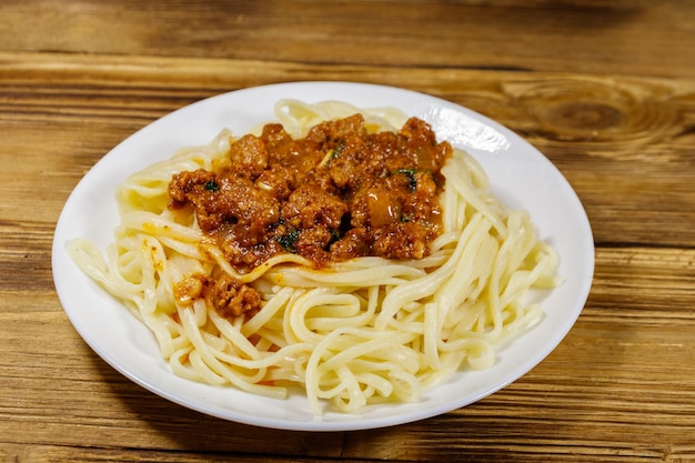 Pasta con salsa boloñesa sobre mesa de madera