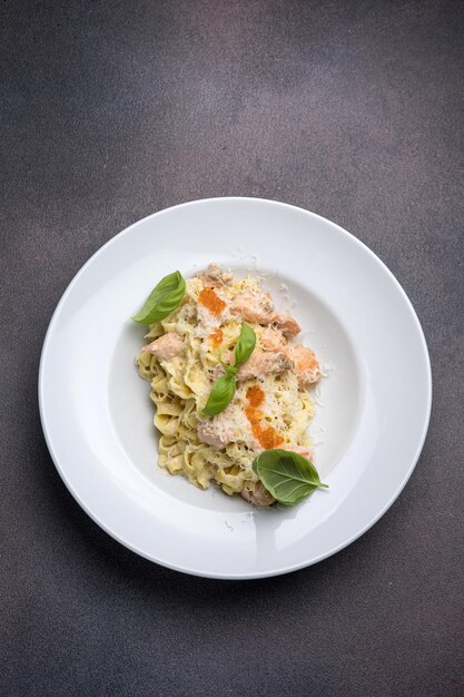 Pasta con salsa de crema de salmón y albahaca en un plato blanco