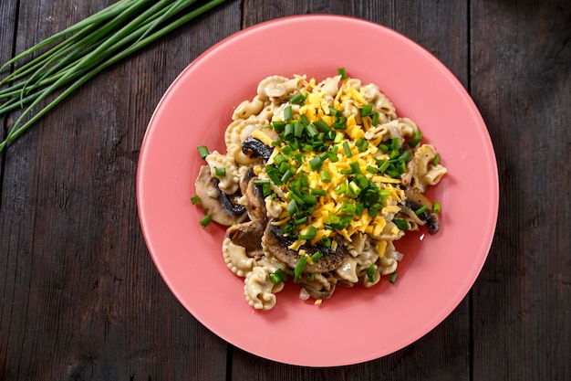 Pasta en salsa cremosa con champiñones en un plato sobre la mesa junto a plumas de cebolla verde