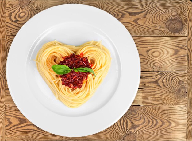 Pasta con salsa en forma de corazón sobre mesa de madera, vista superior