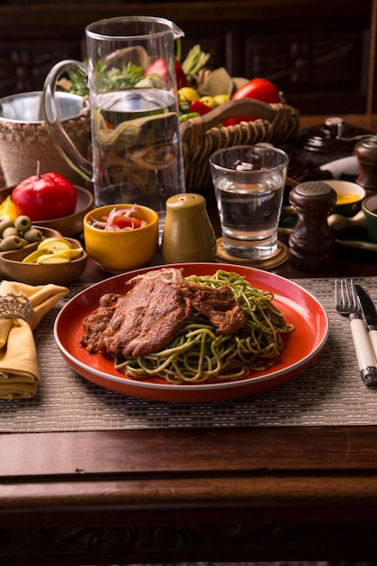 Pasta con salsa pesto verde y chuleta de cerdo Comida reconfortante peruana restaurante gourmet hecho en casa