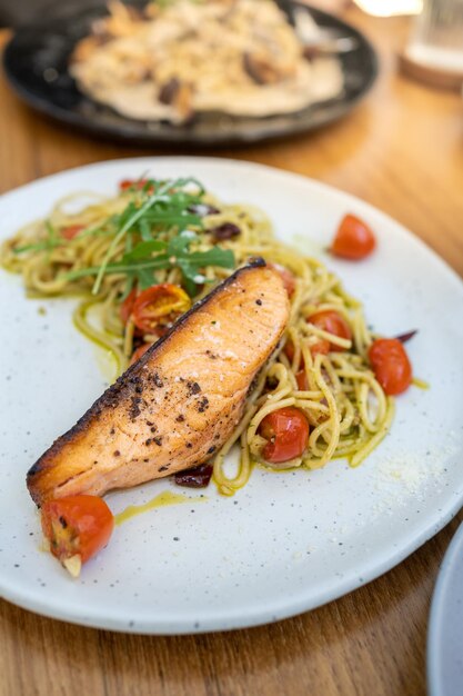 Pasta con salsa de pesto verde espagueti con filete de salmón a la parrilla estilo comida italiana