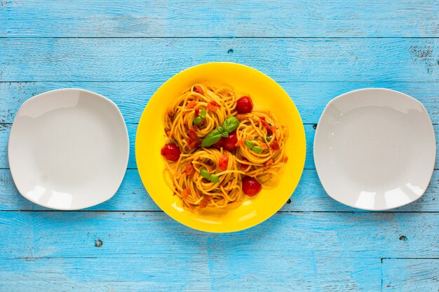 Pasta con salsa de tomate y otros componentes en una madera azul claro