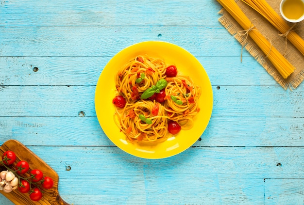 Pasta con salsa de tomate y otros componentes en la mesa de madera azul claro espacio libre para texto.