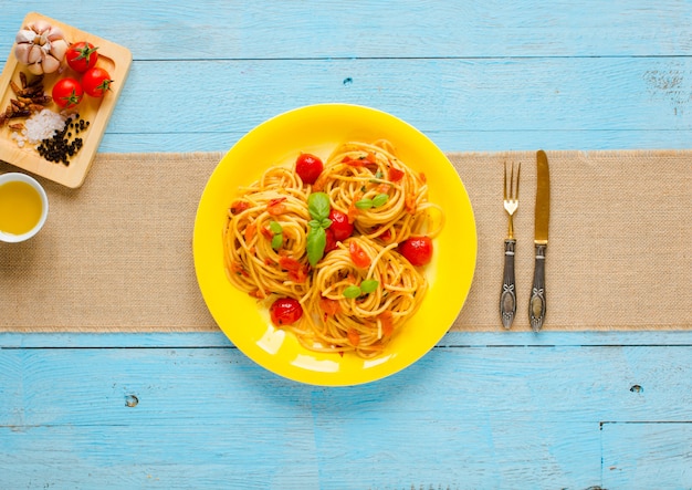 Pasta con salsa de tomate y otros componentes sobre un fondo azul claro de madera espacio libre para texto.