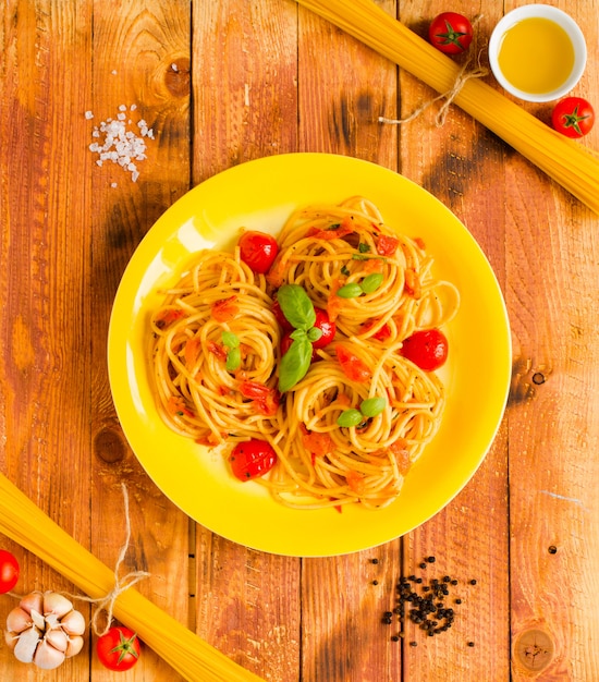 Pasta con salsa de tomate y otros componentes sobre un fondo de madera espacio libre para texto.