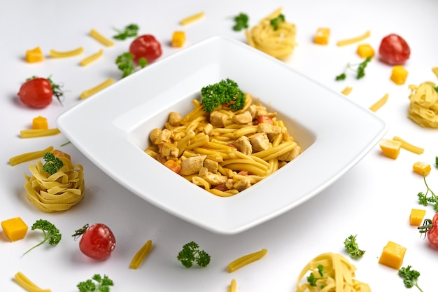 Pasta en salsa de tomate con pollo, tomates decorados con perejil en una placa de madera