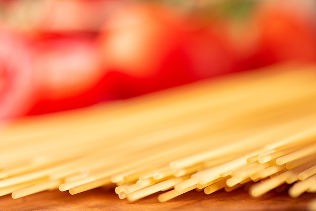 Pasta schöne Details von roten Tomaten und Strängen von rohen Spaghetti über rustikalem Holz selektiven Fokus