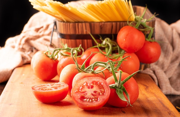 Pasta schöne Details von roten Tomaten und Strängen von rohen Spaghetti über rustikalem Holz selektiven Fokus