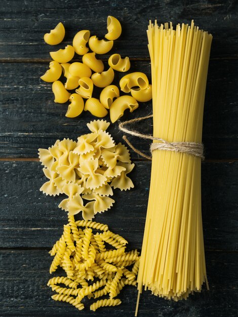 Pasta seca sin tratar Banda de espagueti en mesa oscura