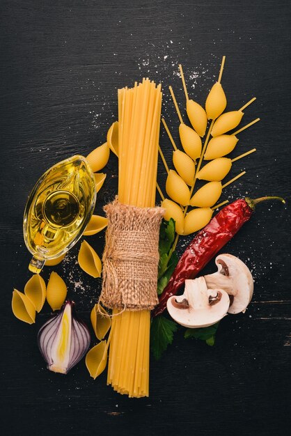 Foto pasta seca con verduras frescas y especias en forma de espiguilla de trigo sobre un fondo de madera vista superior espacio de copia