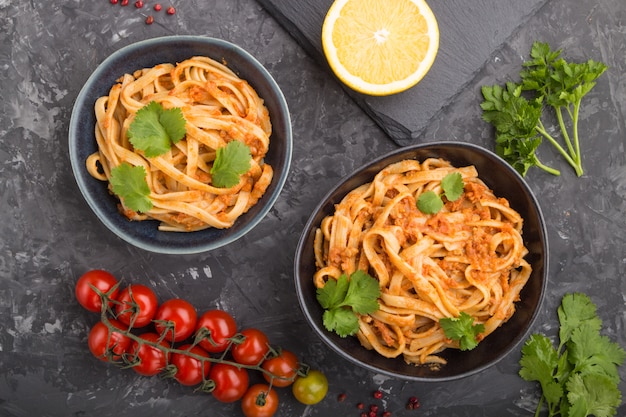 Pasta de sémola con salsa de pesto de tomate, naranja y hierbas sobre una superficie de hormigón negro. vista superior, de cerca.