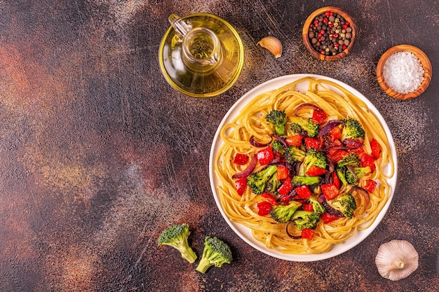 Pasta servida con salsa de verduras de brócoli, cebolla y pimiento de colores