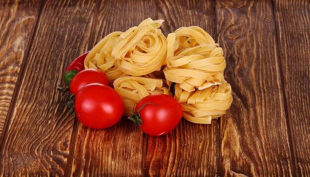 Pasta sobre fondo de madera con tomate