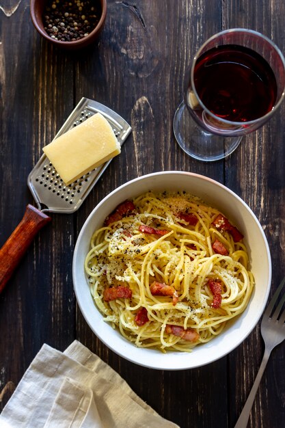 Pasta Spaghetti Carbonara auf einem Holztisch. Italienische Küche. Rezept. Rustikaler Stil. Wein.