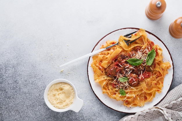 Pasta tagliatelle con albóndigas en salsa de tomate y tomillo en salsa sobre pizarra gris claro, piedra o fondo de hormigón. Plato y cocina tradicional italiana. Vista superior con espacio de copia.