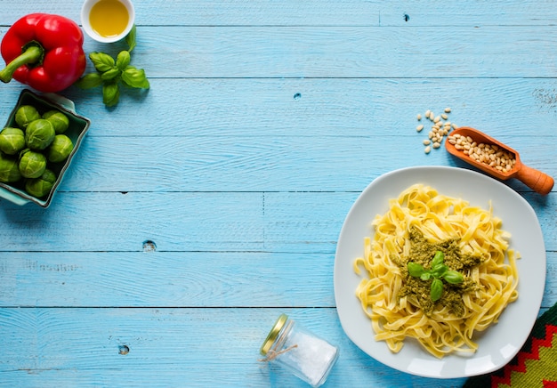 Pasta Tagliatelle mit Pesto-Sauce und anderem Gemüse auf einem Holzhintergrund. Draufsicht