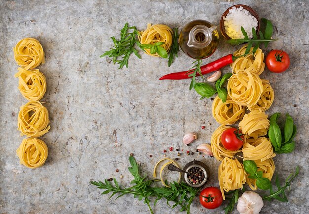 Pasta Tagliatelle nido e ingredientes para cocinar (tomates, ajo, albahaca, chile). Vista superior