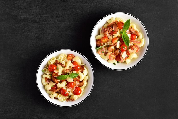 Pasta con tocino, tomate, queso parmesano y hojas de albahaca