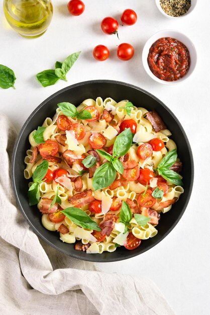 Pasta de tomate y tocino con queso parmesano y hojas de albahaca