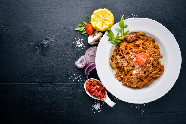 Pasta con tomates cherry, aceitunas y champiñones con queso parmesano Comida italiana En una superficie de madera negra Espacio libre para su texto Vista superior