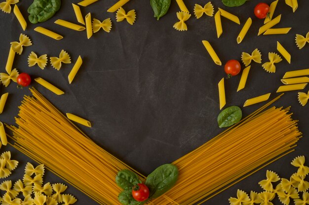 Pasta con tomates cherry y espinacas sobre fondo blanco endecha plana