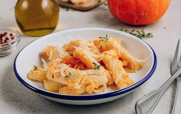 Pasta tortiglioni de calabaza asada cremosa con queso parmesano y tomillo sobre fondo de hormigón Enfoque selectivo