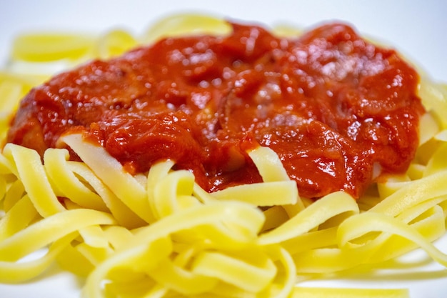 Foto pasta tradicional de tagliarini com salsicha de tomate e queijo parmesão