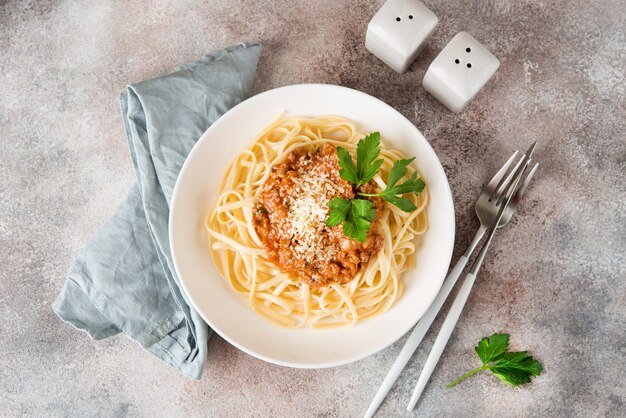 Pasta tradicional italiana con salsa boloñesa en un plato blanco, vista superior