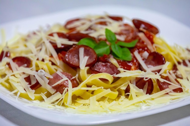 Pasta tradicional de tagliarini con salchicha de tomate y queso parmesano